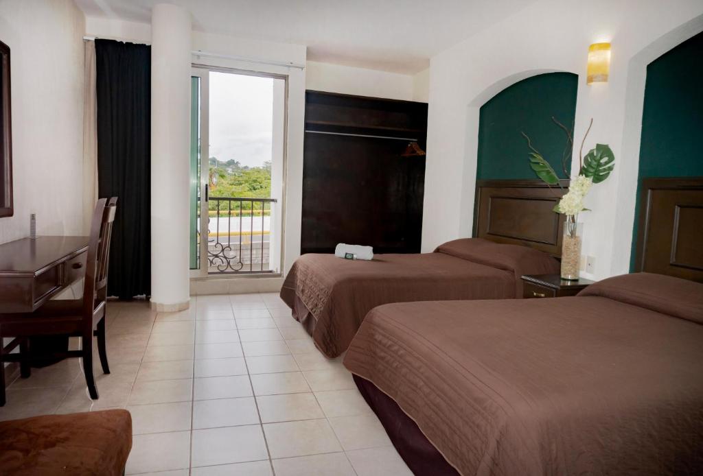 伊达尔戈州波萨里卡Hotel Du Parc的酒店客房设有两张床、一张书桌和一个窗户。