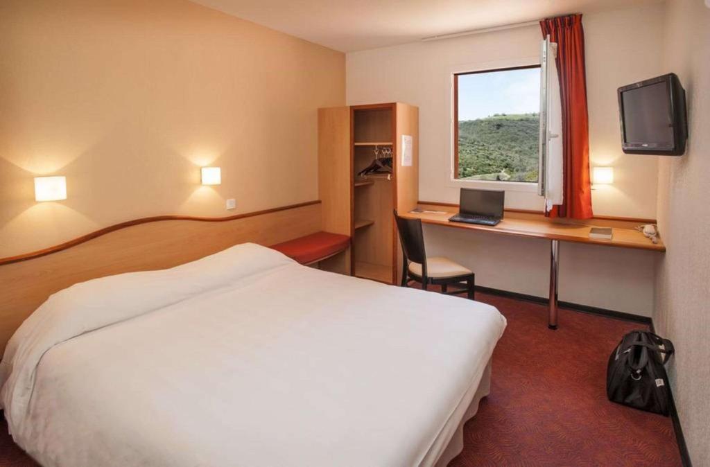 蒙托邦Brit Hotel Confort Montauban的酒店客房配有一张床和一张带电脑的书桌