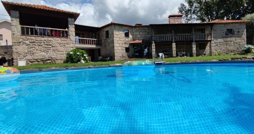 布拉加Casa das Oliveiras的一座大蓝色游泳池,位于房子前