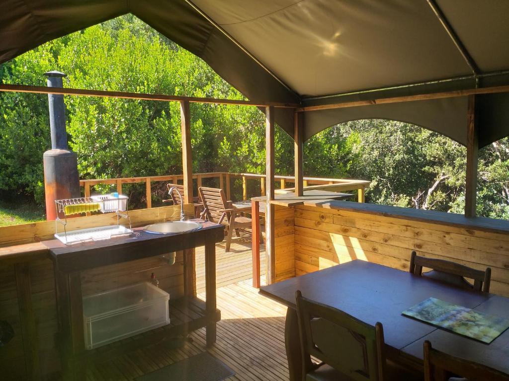 维德尼斯Wilderness Glamping Tents的户外甲板设有烧烤架和桌椅