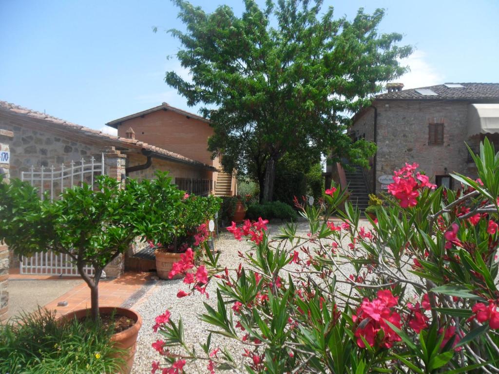 锡耶纳富丽诺尼罗尔塔旅游公寓酒店的一座花园,在一座建筑前方种有粉红色花卉