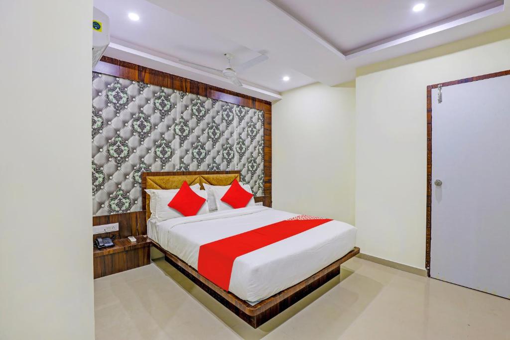巴罗达OYO Hotel Golden的一间卧室配有一张带红色枕头的大床