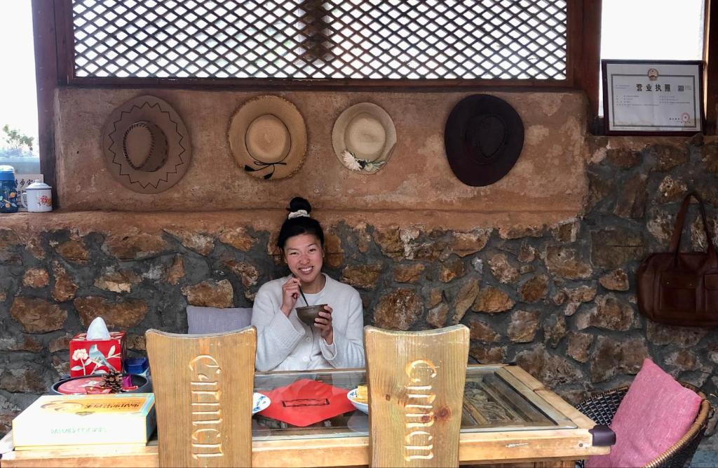 丽江Lijiang Jayden Lodge臣安山居民宿 - Namaste的坐在桌子旁看着手机的女人