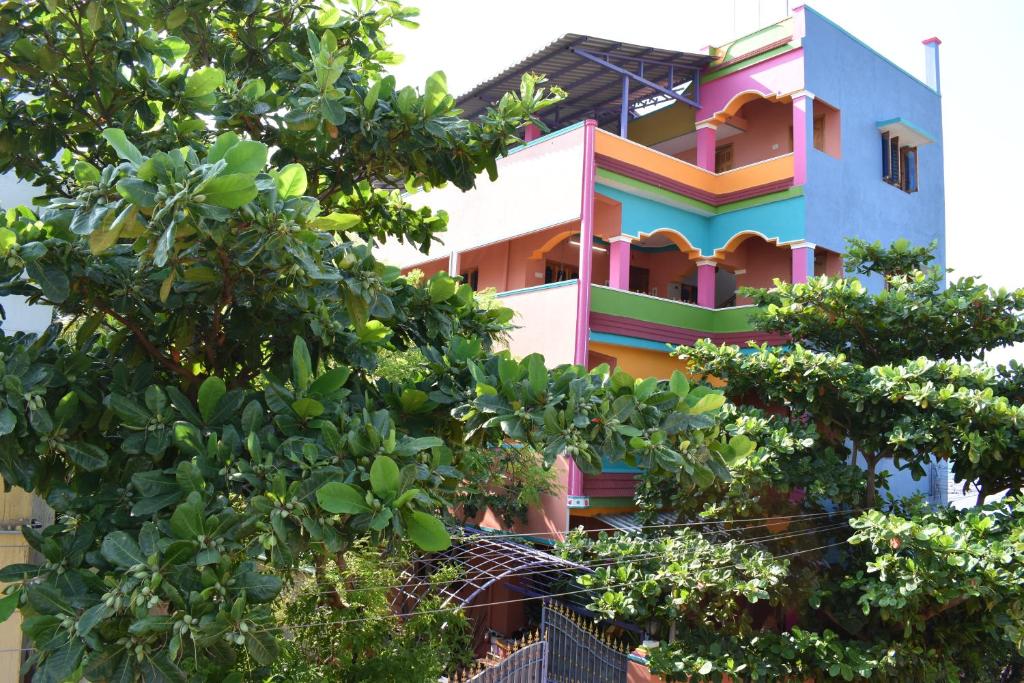 蒂鲁瓦纳马莱Rainbow Guest House的一座五颜六色的建筑,前面有树木