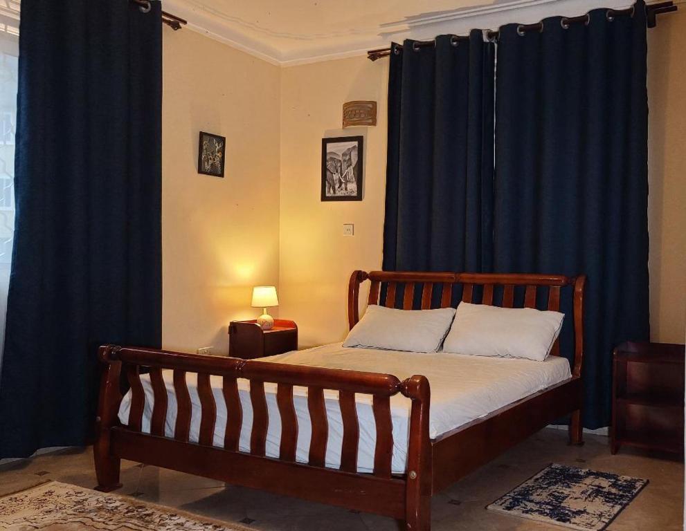 坎帕拉HIS&HERS MOTEL by MATHIAS的一间卧室配有一张蓝色窗帘的床