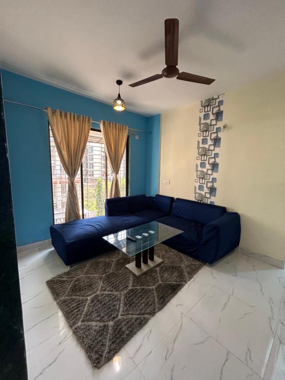 纳威孟买La Residence的客厅配有蓝色的沙发和玻璃桌
