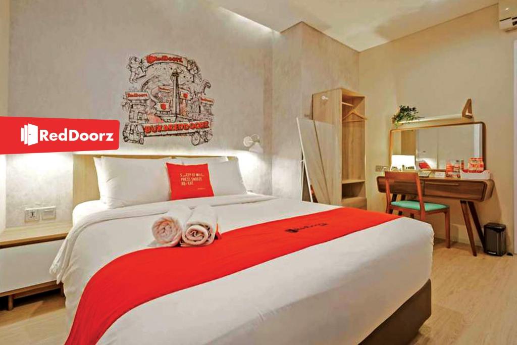 班达楠榜Arwana Inn Lampung RedPartner的一间卧室配有一张大床、书桌和红色边界