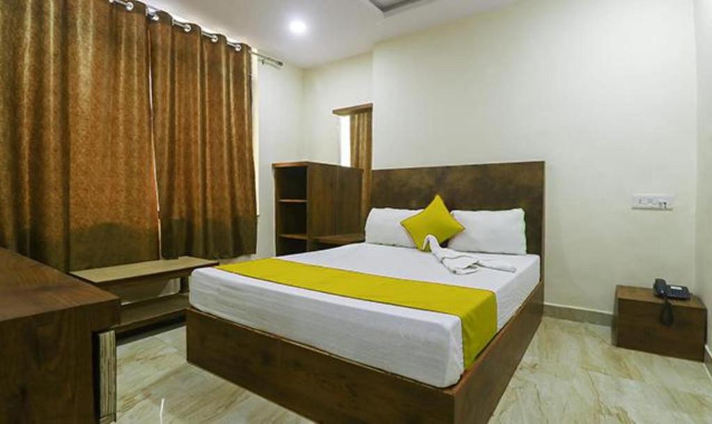 瓜廖尔FabHotel Rama Inn I的一间卧室配有一张带黄白色床单的大床