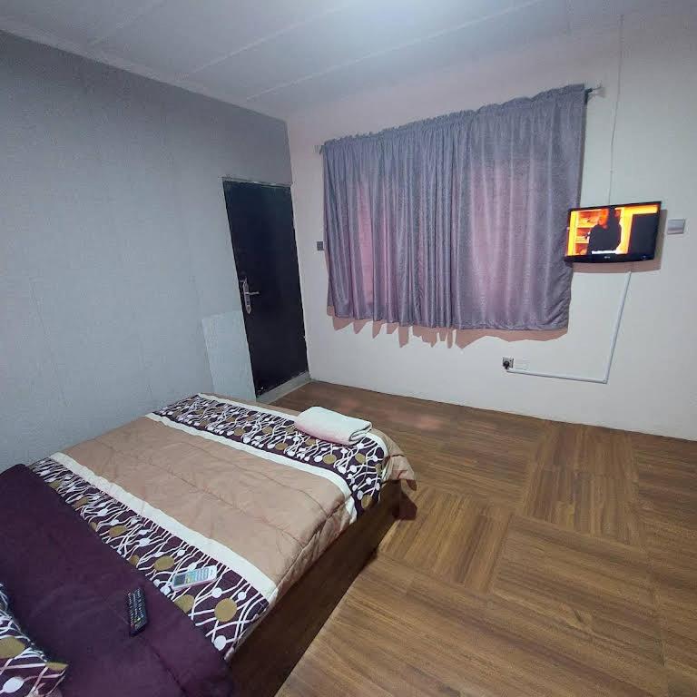 伊巴丹Diek Guest House的一间卧室配有一张床、一台电视和一个窗口