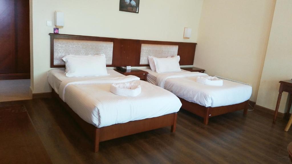 廷布Whispering Woods Resort的酒店客房,配有两张带白色床单的床