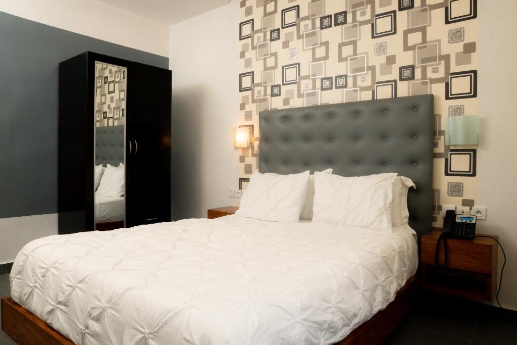 雅温得CINCINNATI HOTEL YAOUNDE的卧室配有白色的床和大镜子