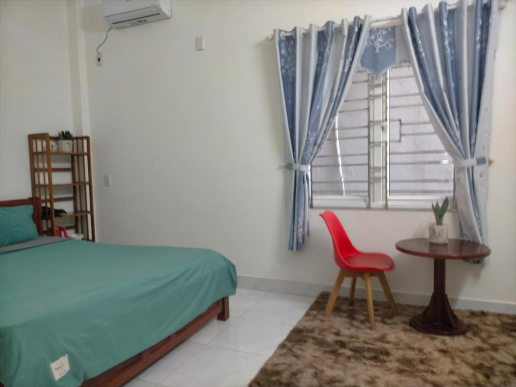 岘港TN's House的一间卧室配有一张床、一张红色椅子和一个窗户