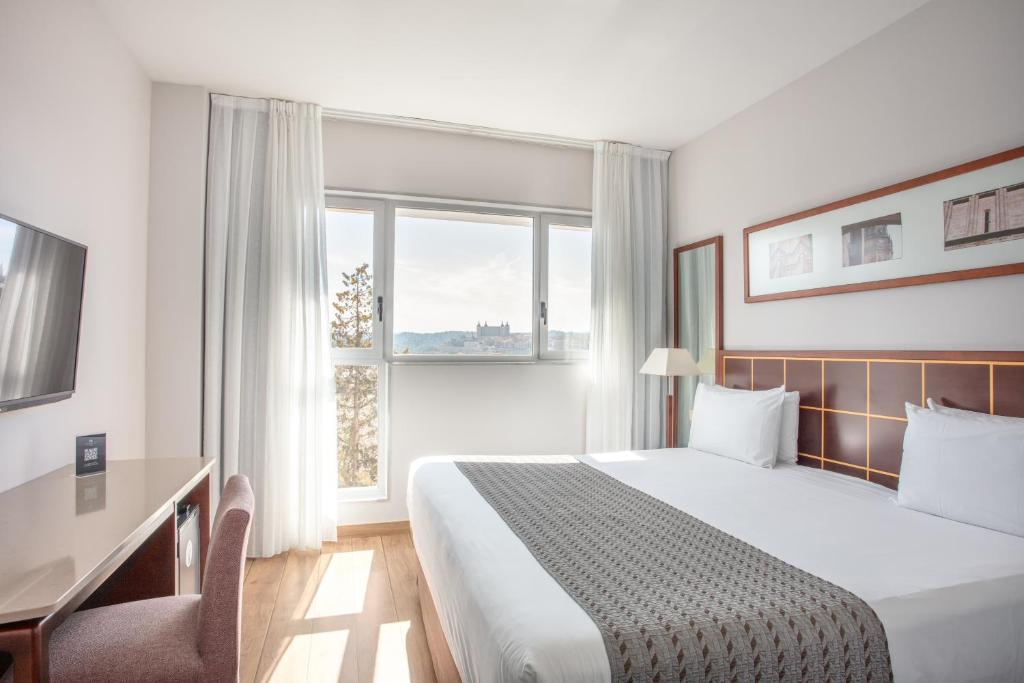 托莱多托莱多欧洲之星酒店的配有一张床、一张书桌和一扇窗户的酒店客房
