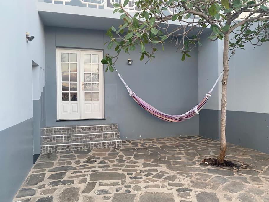 明德卢Vivenda com pátio, no coração do Mindelo的建筑物前带吊床的树