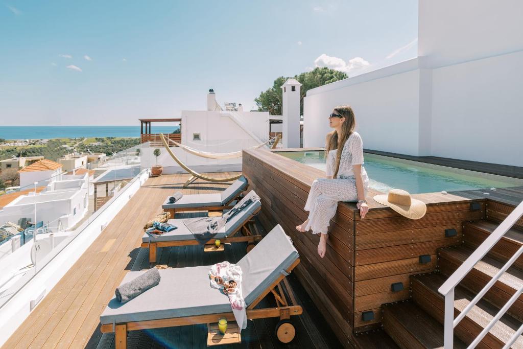 卡拉索斯Kalathos Square luxury suites的坐在游艇上阳台边缘的女人