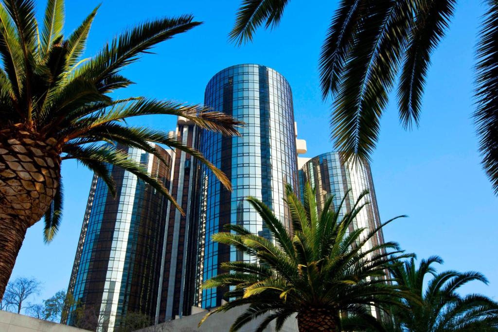 洛杉矶The Westin Bonaventure Hotel & Suites, Los Angeles的一座高大的建筑,前面有棕榈树