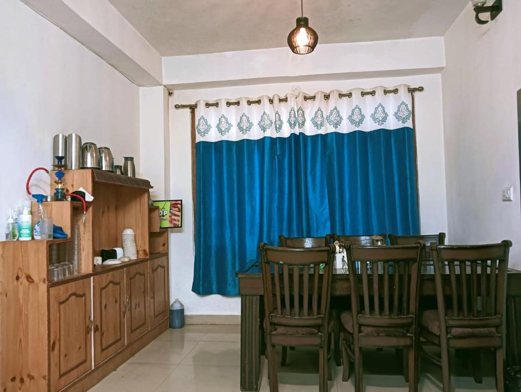 西姆拉The White House Shimla的一间设有蓝色窗帘和桌椅的用餐室