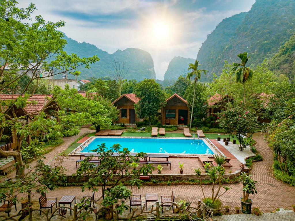 宁平Tam Coc Rocky Bungalow的一座带游泳池和山脉的度假村