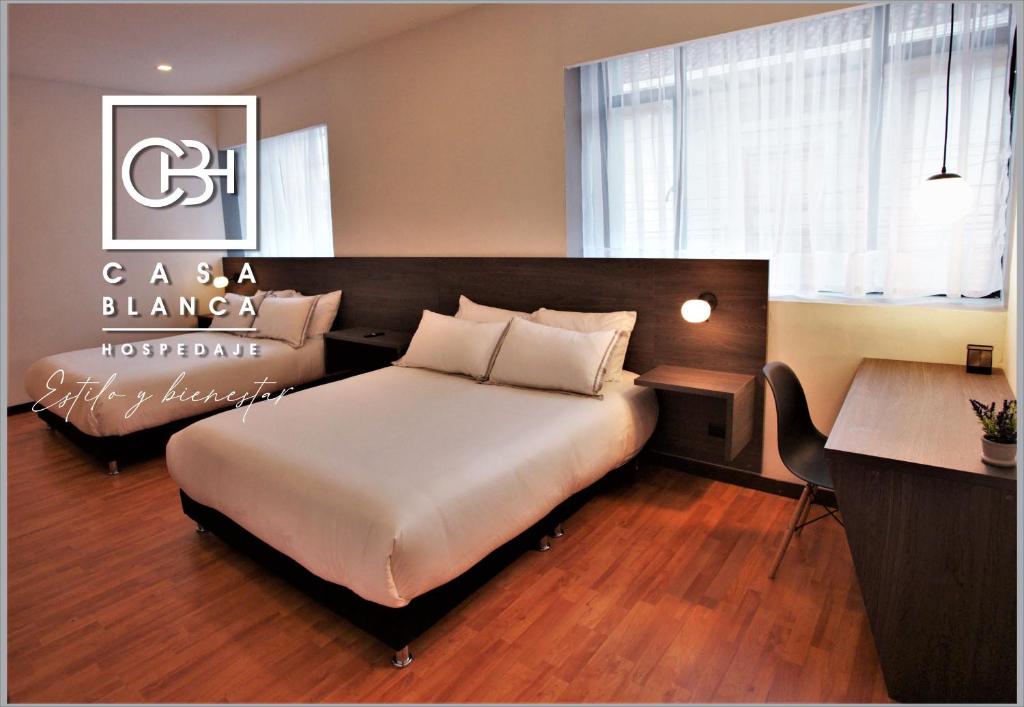 帕斯托Casa Blanca Hospedaje的一间卧室配有一张大床、一张桌子和一张书桌