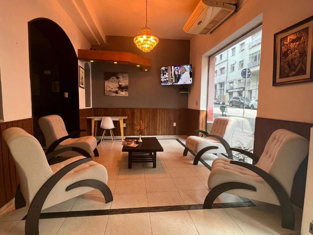蒙得维的亚HOTEL MEDITERRANEO的一间设有椅子和电视的等候室