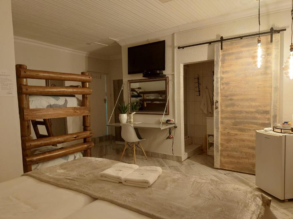KraaifonteinVilla Mariss Guesthouse的一间卧室配有一张床、一张书桌和一台电视