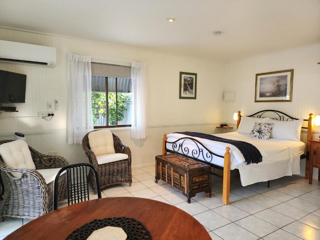 ChillagoeChillagoe Cabins and Tours的一间卧室配有一张床、一把椅子和一张桌子