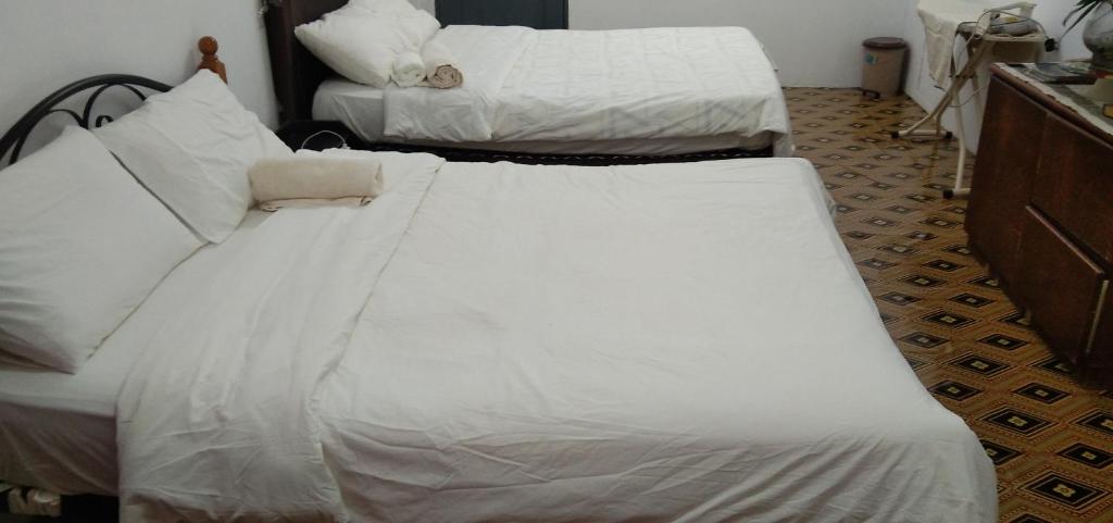 Kampong ParitMelrose homestay and transport的一间卧室配有两张带白色床单的床