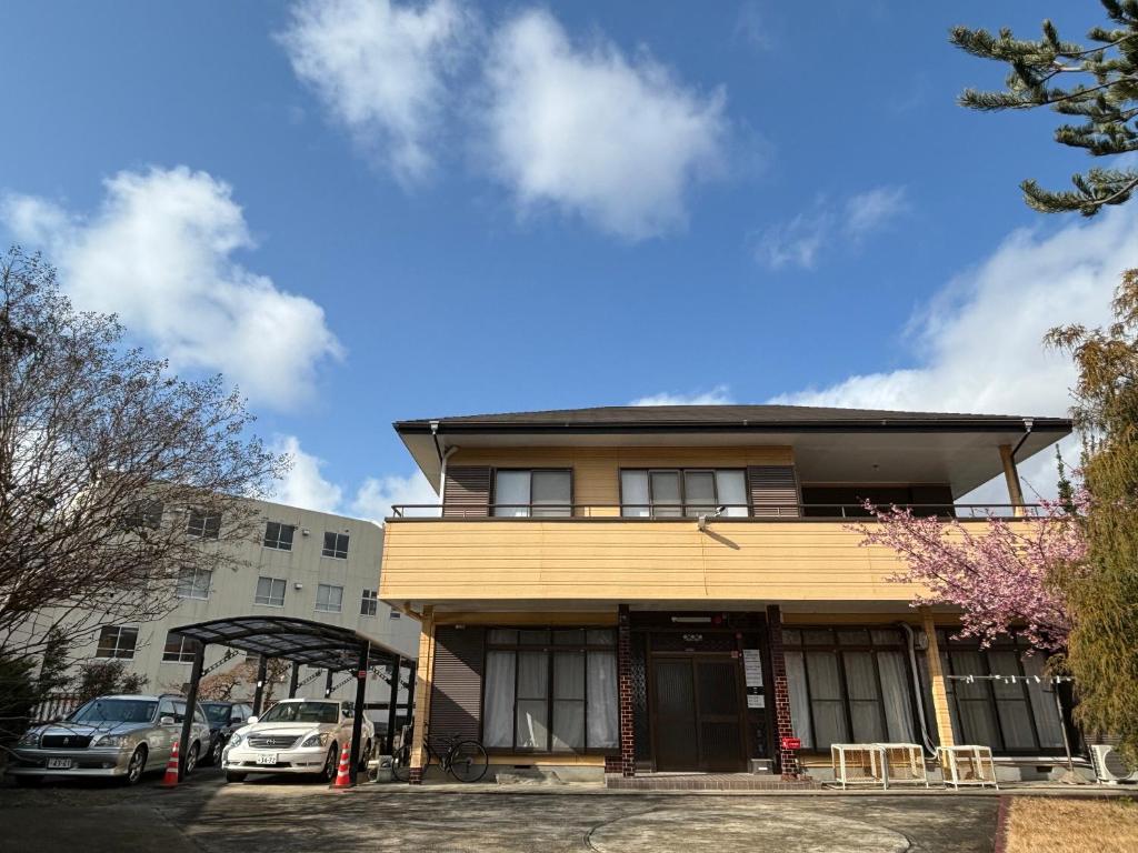 水户一棟貸しの宿 貸別荘 水戸ハウス Vacation Rental Mito House的两辆车停在大楼前的建筑物