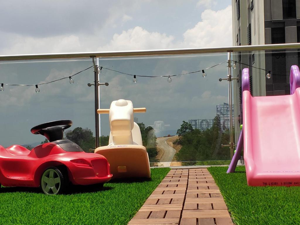 努沙再也D Bunga 1 MOSLIM Homestay Pool View Legoland Nusajaya的坐在椅子旁的草上的一个红色玩具车