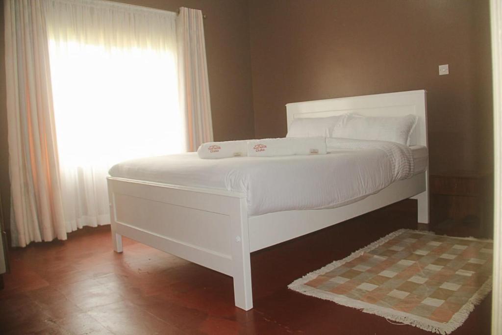 KiganjoChaka Homes的窗户客房内的一张白色床