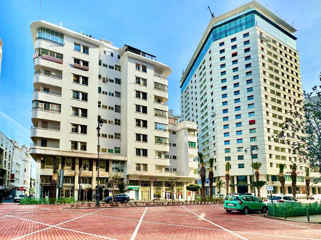 卡萨布兰卡Casablanca Central Suites - Casa Port的两座高楼,有车停在停车场