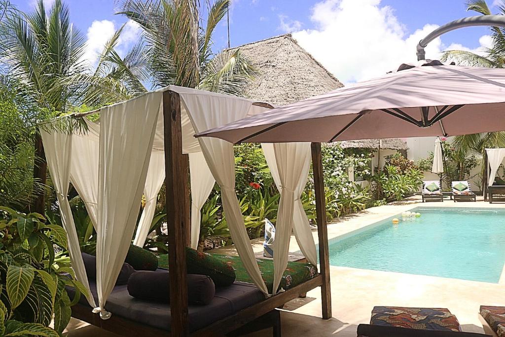 江比阿Aurora Boutique Hotel Jambiani的游泳池旁配有遮阳伞和椅子的游泳池
