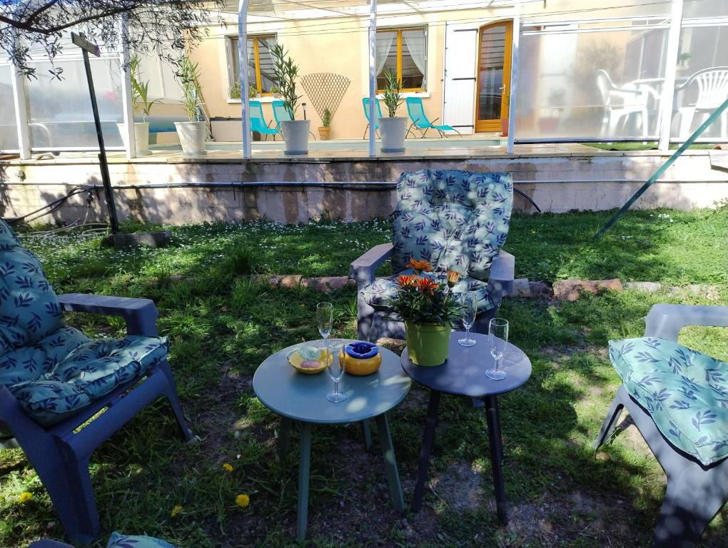 瓦隆蓬达克Gites l’Olivier avec piscine的庭院设有两把椅子和两张桌子,配有酒杯