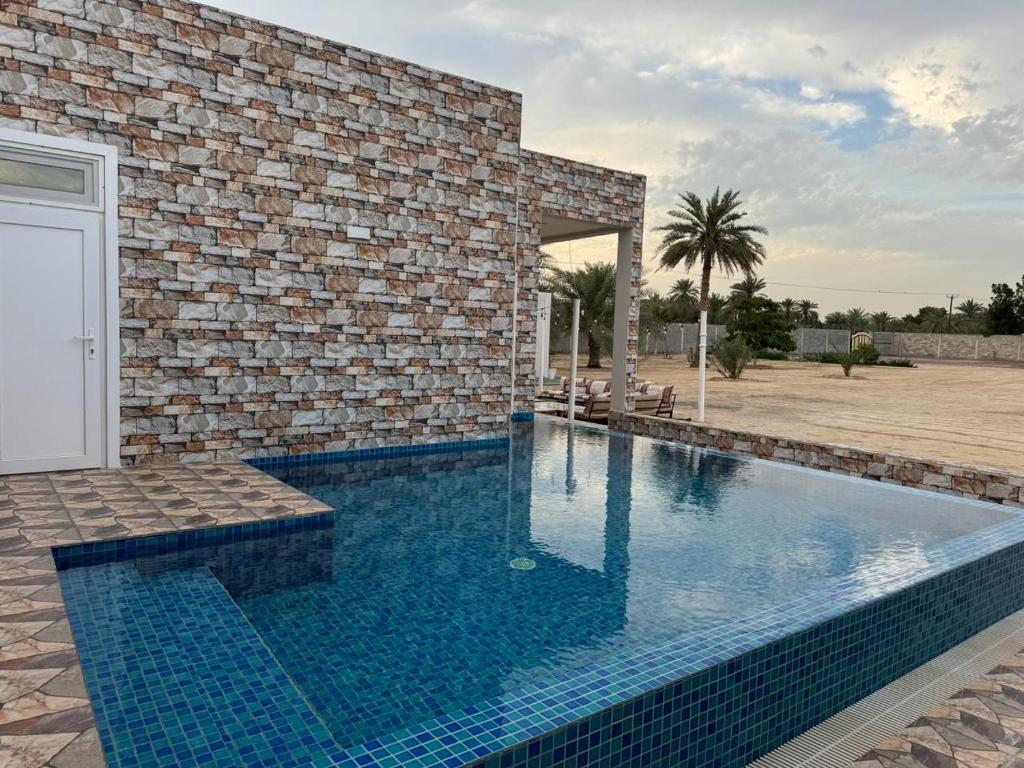 Al RahbaRashed Farm的砖楼前的游泳池