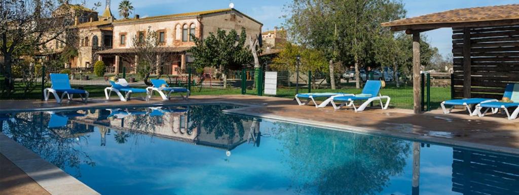 Serra de DaróCan Pujol - Turismo Rural的一个带蓝色椅子的游泳池