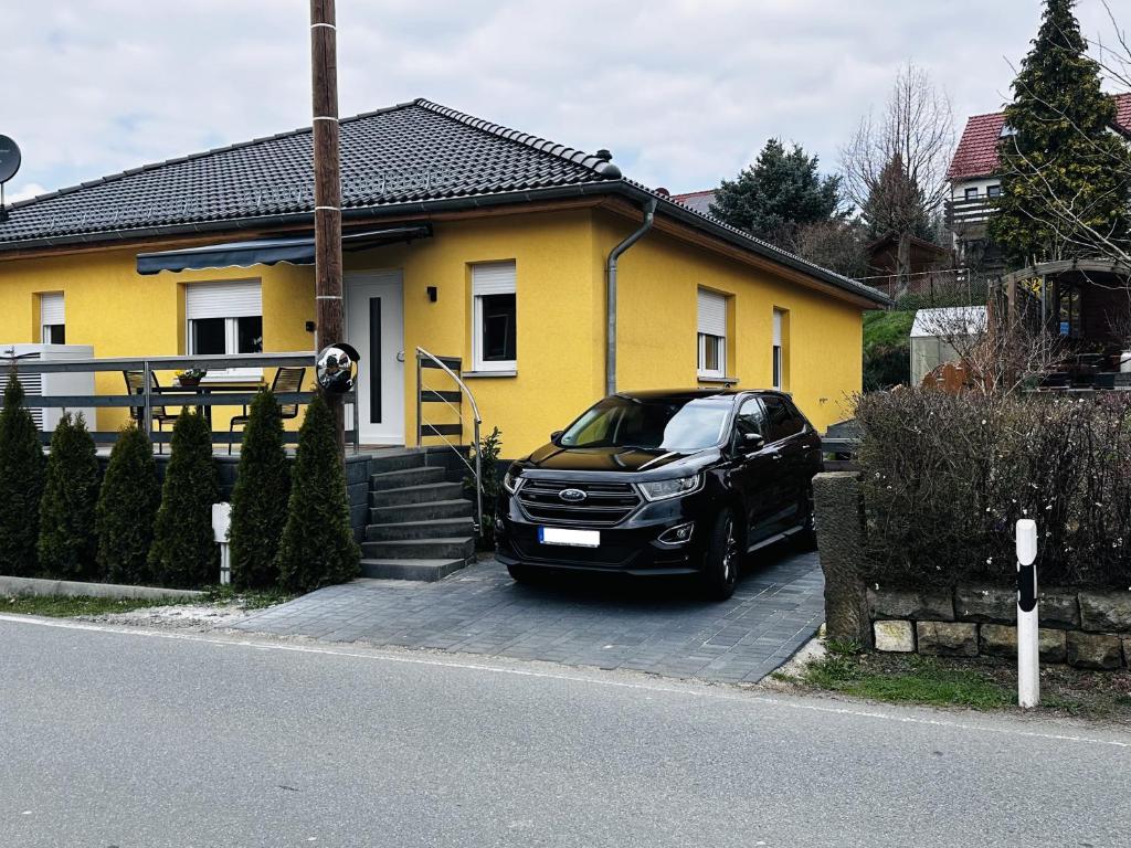 StruppenFischis Ferienwohnung Struppen的停在黄色房子前面的一辆黑色汽车