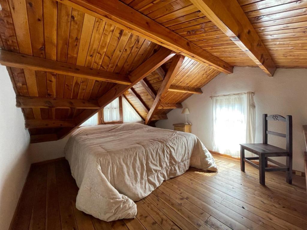 圣卡洛斯-德巴里洛切Casa para descansar的卧室设有木制天花板、一张床和椅子