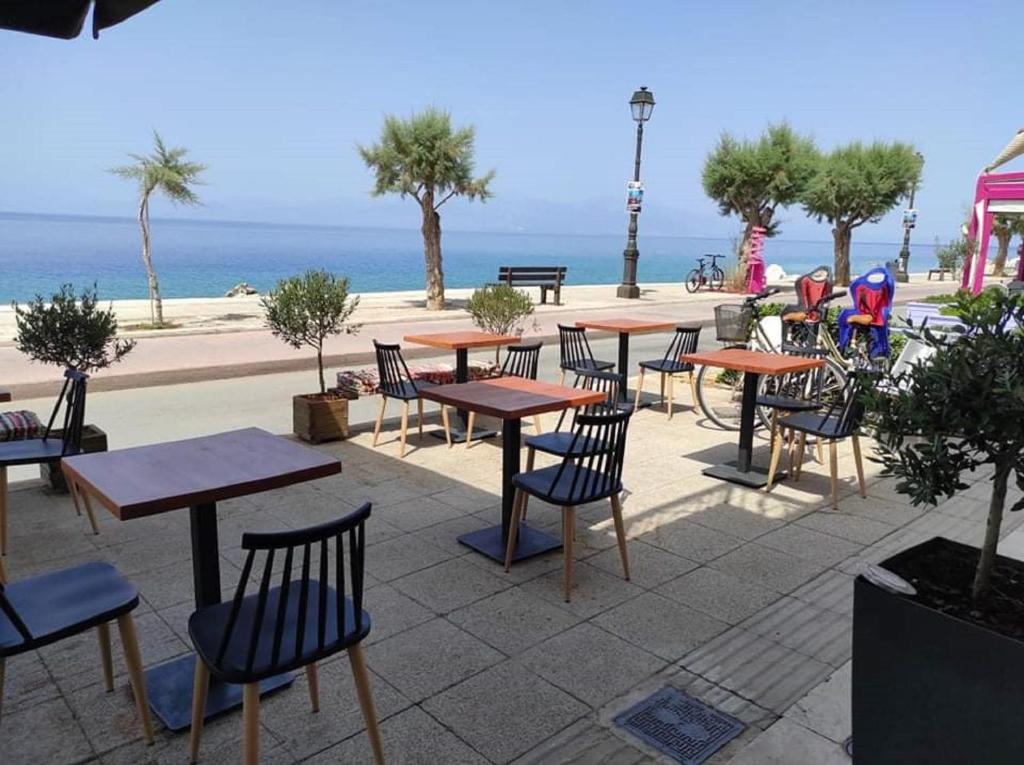 西洛卡特伦Hotel Kyani Akti的一组桌子和椅子,背景是海洋