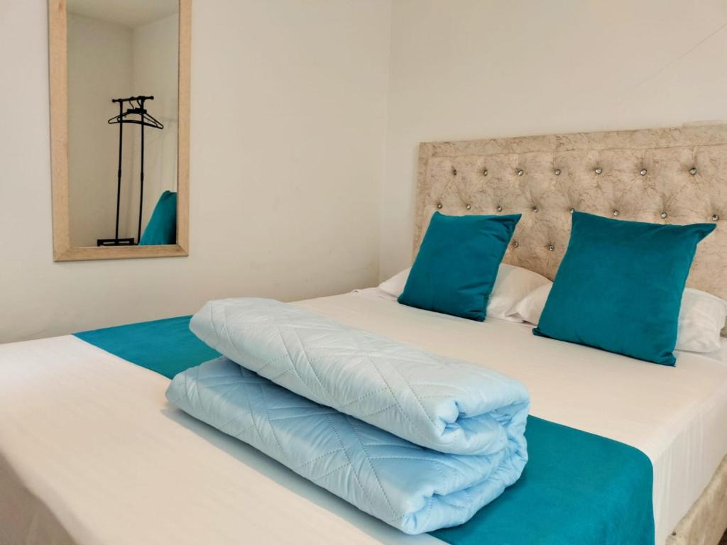 波哥大Hotel Batan 127的两张带蓝色枕头的床铺,彼此相邻