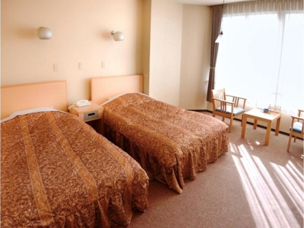 鸟取市Tottori Onsen Shiitake Kaikan taisuikaku - Vacation STAY 21954v的酒店客房设有两张床和窗户。