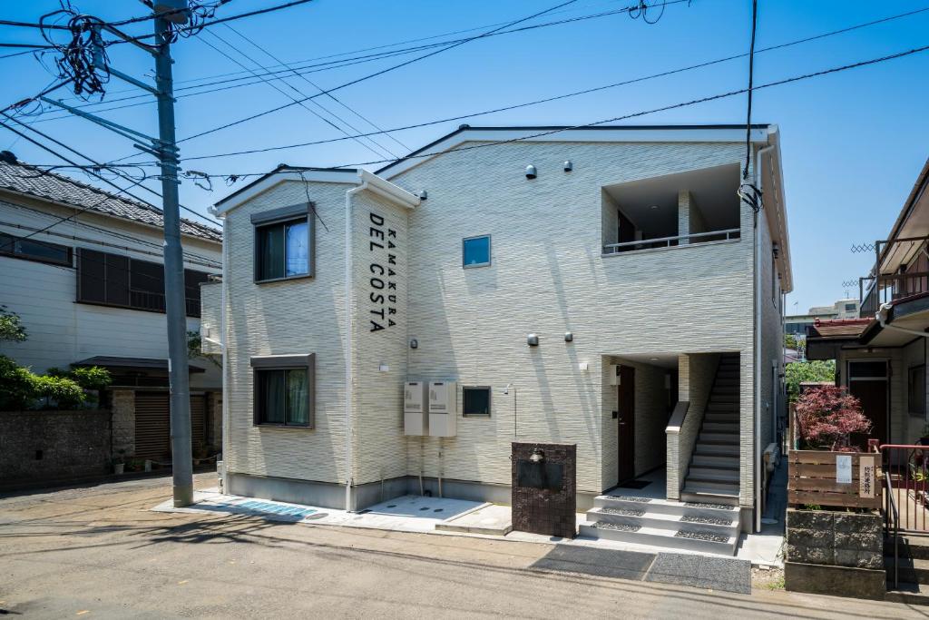 镰仓市KAMAKURA DEL COSTA的白色砖砌建筑,上面有标志