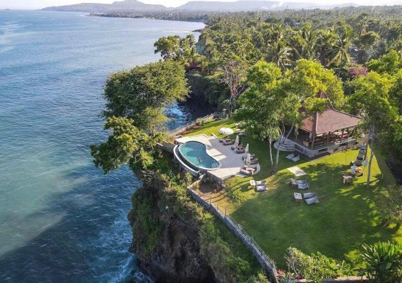 卡朗阿森Bali Cliff Glamping的靠近大海悬崖上房屋的空中景观