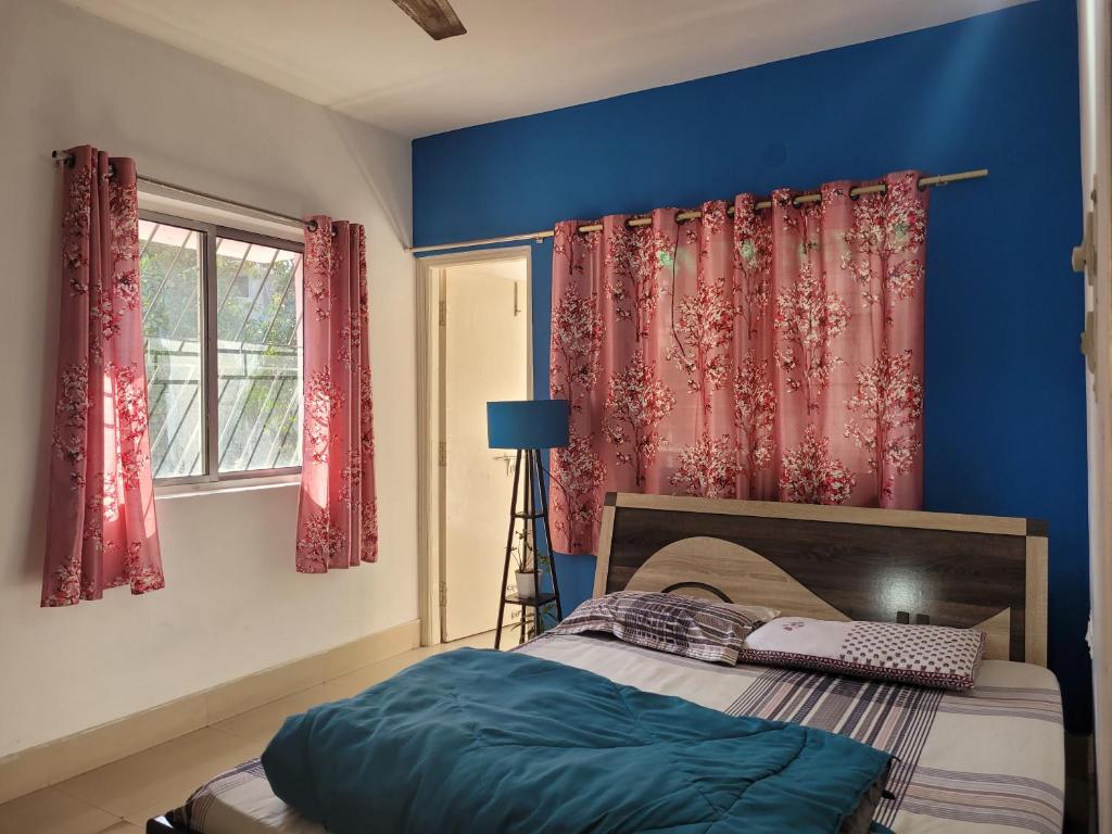 兰奇Mysa Homestay的一间卧室配有一张蓝色墙壁和红色窗帘的床