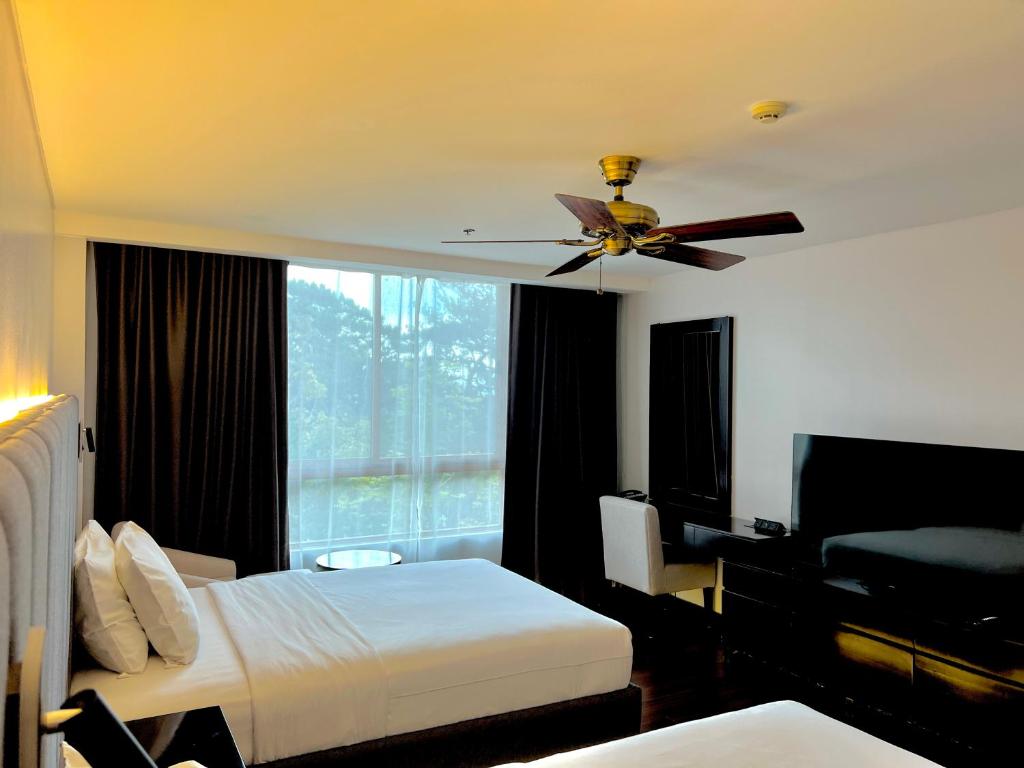 碧瑶Forest Lodge at Camp John Hay privately owned - Deluxe Queen Suite with balcony and Parking 269的酒店客房设有吊扇和一间卧室。