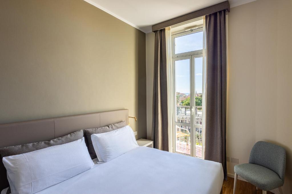 博尔迪盖拉伊莉莎Spa别墅酒店的一间卧室设有一张床、一个窗口和一把椅子