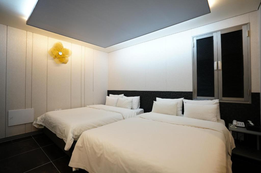 首尔Shinchon Y Hotel的配有2张床铺的白色床单和黄色气球