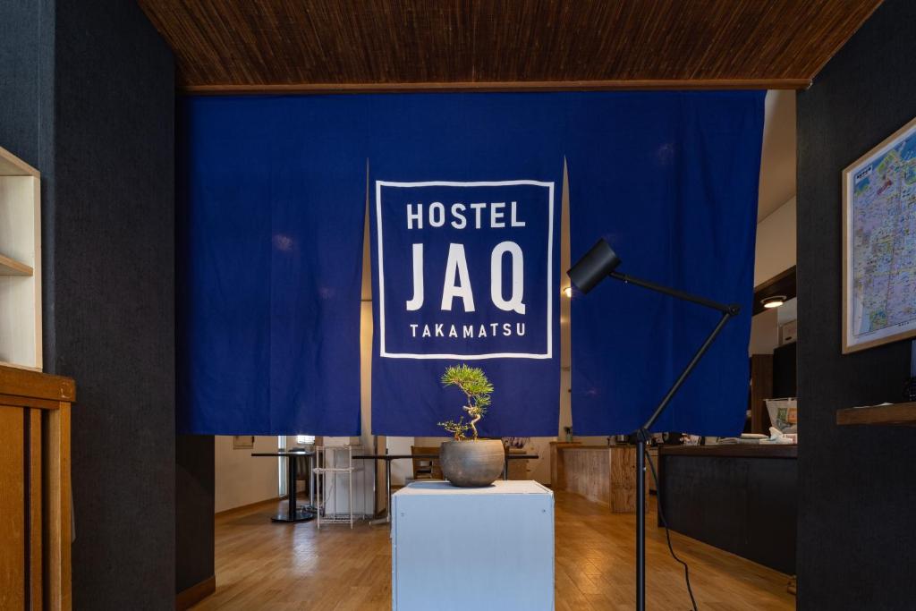 高松Hostel JAQ takamatsu的蓝墙,上面有读旅馆雅各的标志