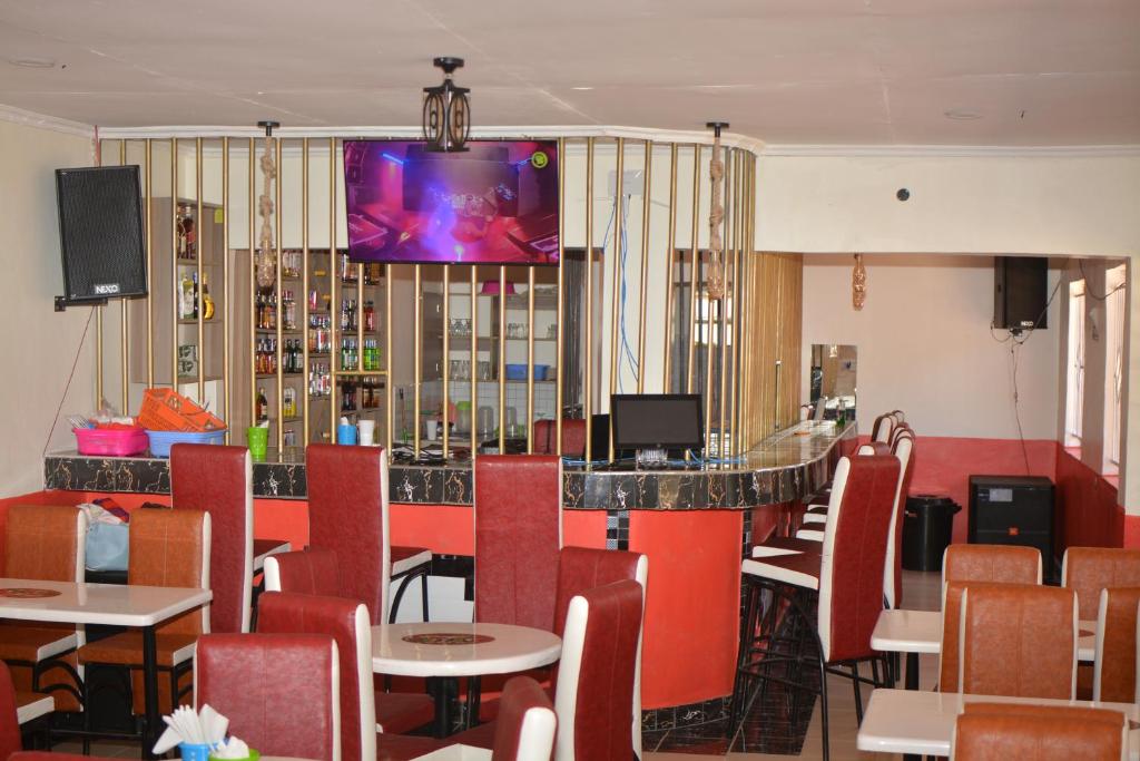 KakamegaTHE FARM BAR AND RESTAURANT的餐厅设有酒吧,墙上配有电视。