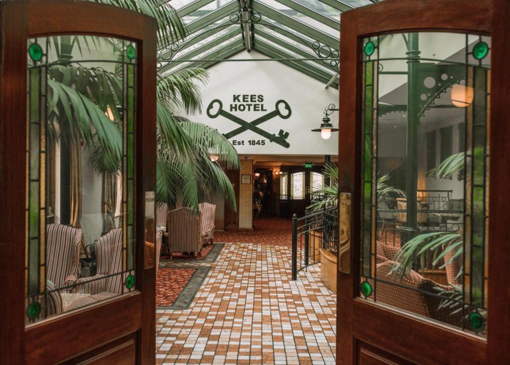 斯特拉诺勒Kee's Hotel的大堂设有带桌椅的温室