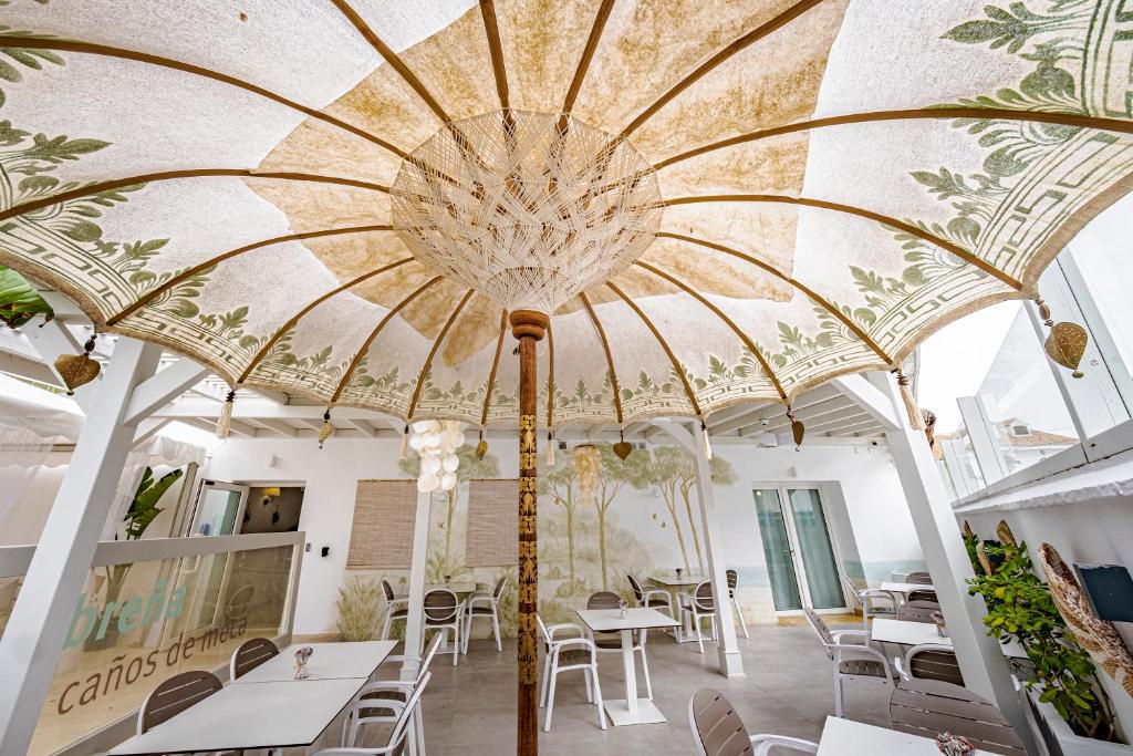 洛斯卡尼奥斯德梅卡Labreña Hotel的餐厅拥有带桌椅的大型天花板。